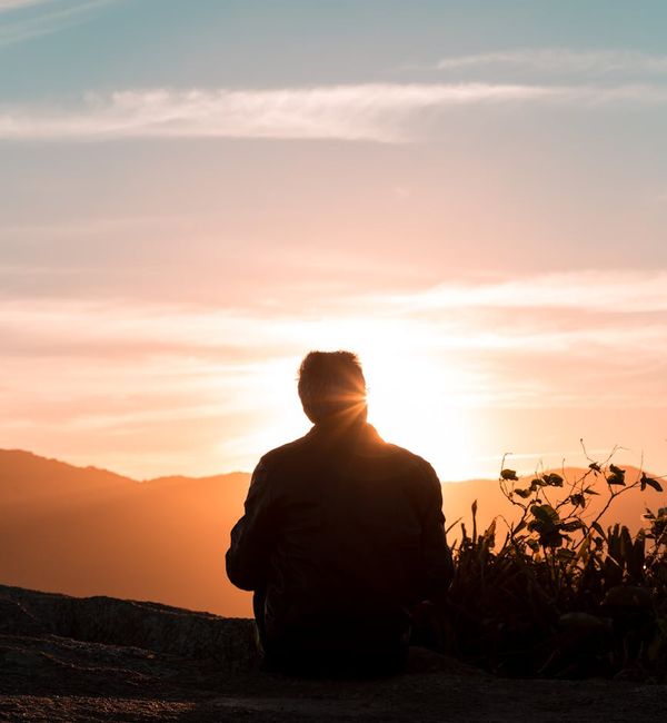 Silhouette of a person meditating against a beautiful sunset sky.